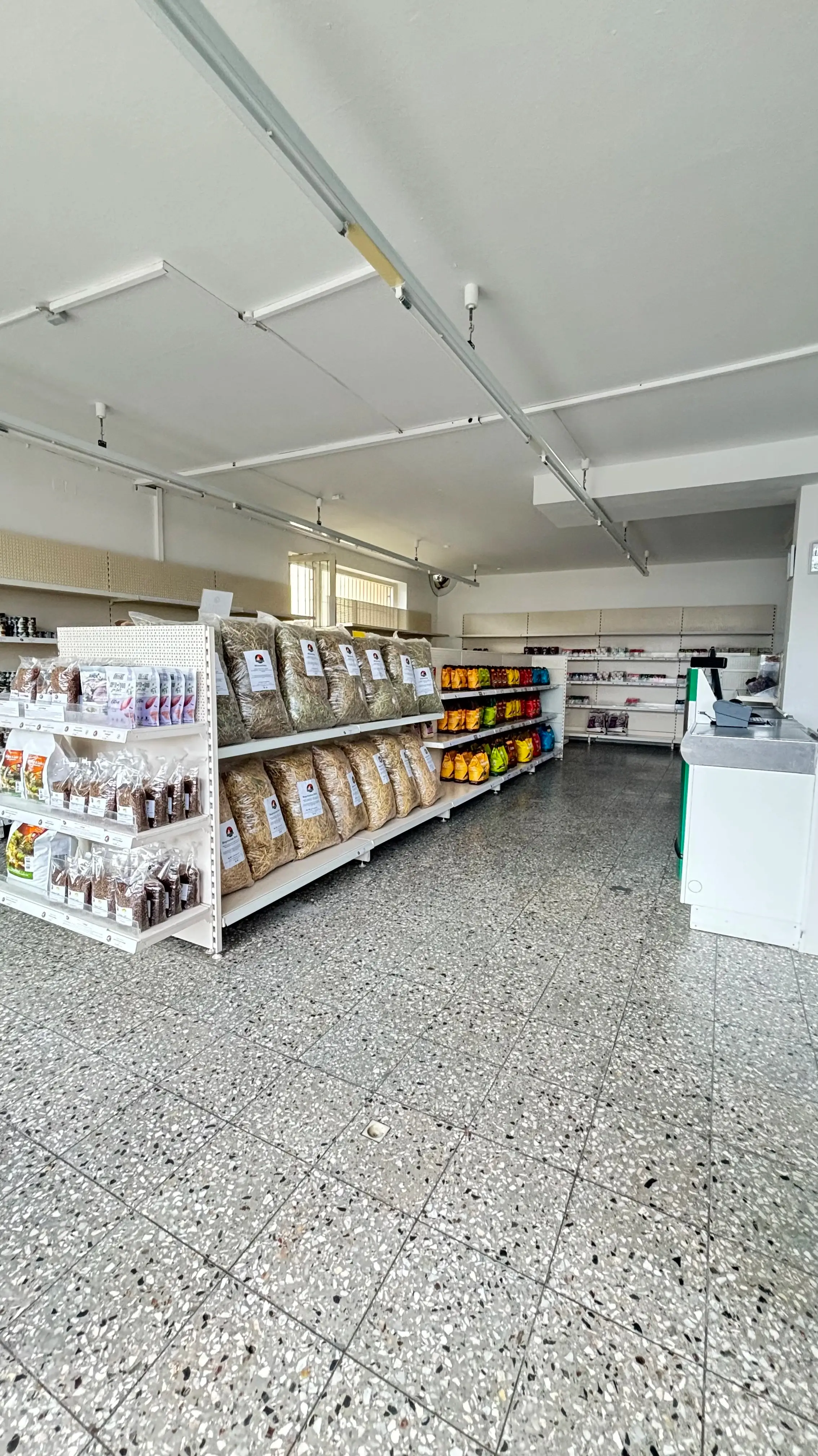 Regale mit Futter und Kausnacks sowie die Kasse im Ladeninneren